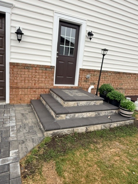 Three-tier paver entry steps with charcoal treads and natural stone risers leading to a back door