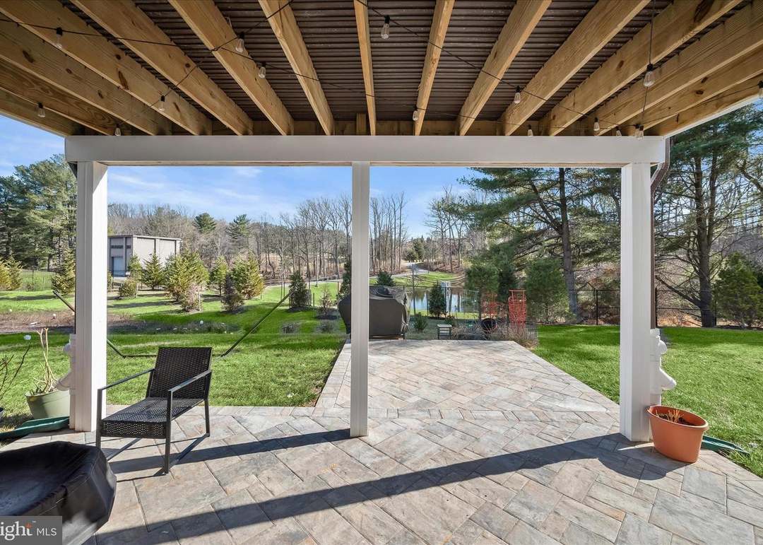 Under-deck paver patio in a herringbone pattern overlooking a backyard pond
