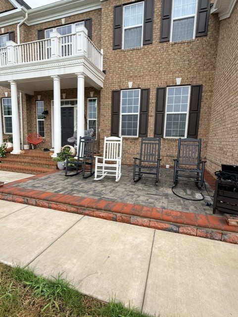 Front paver patio with a red clay soldier-course border wrapping the porch of a brick colonial home